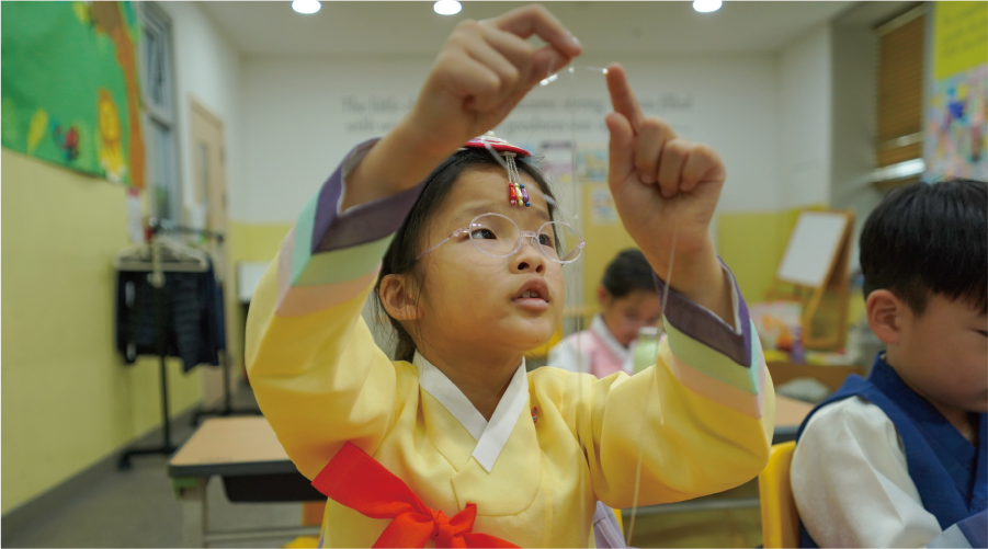 JCS Elementary Korean Language & Literature Elementary school student wearing a hanbok and learning about traditional culture during a regular curriculum Korean & Literature class